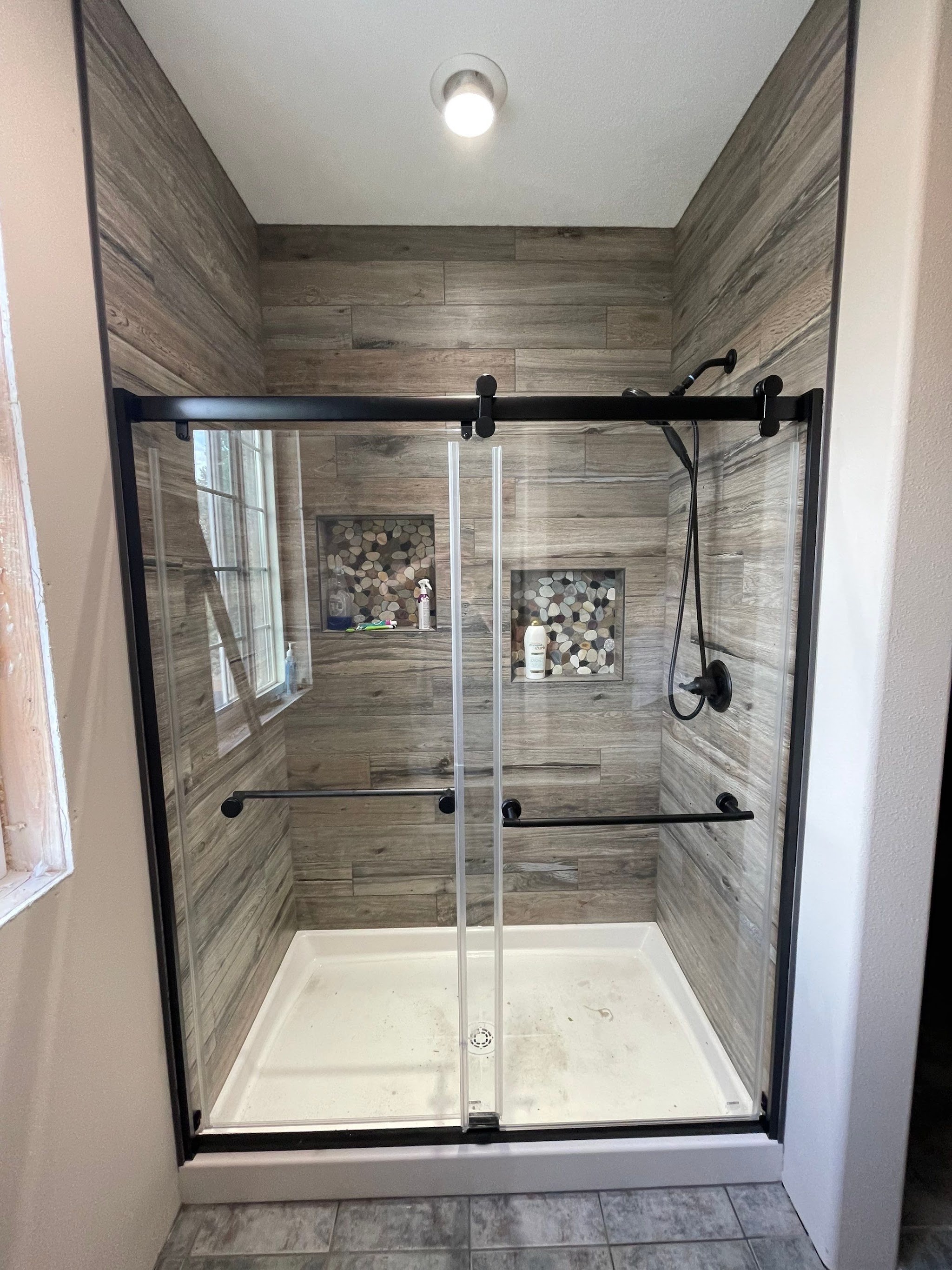 A finished tiled shower with a frameless sliding glass door