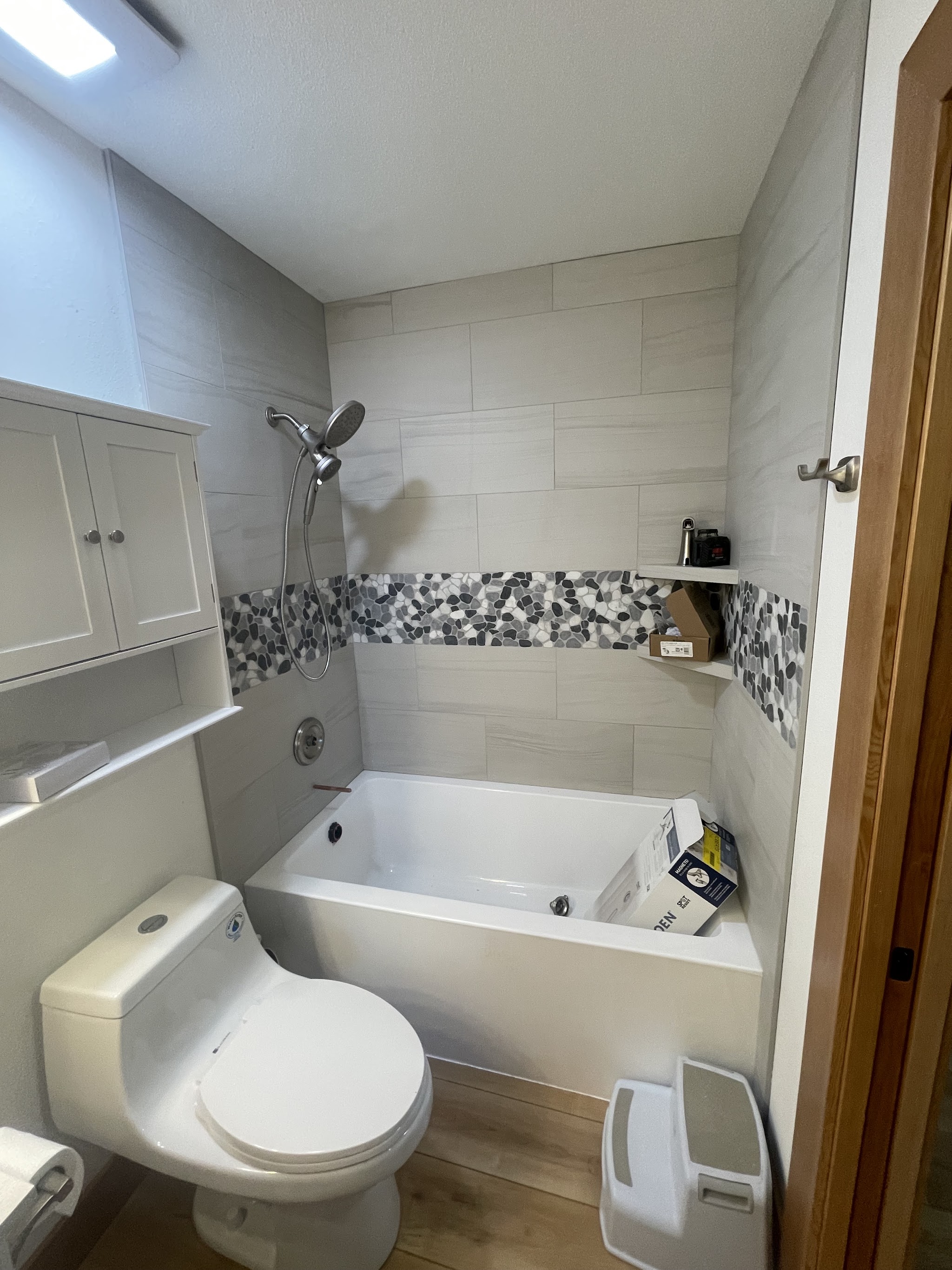 A finished tub and shower surround with a pebble tile accent band