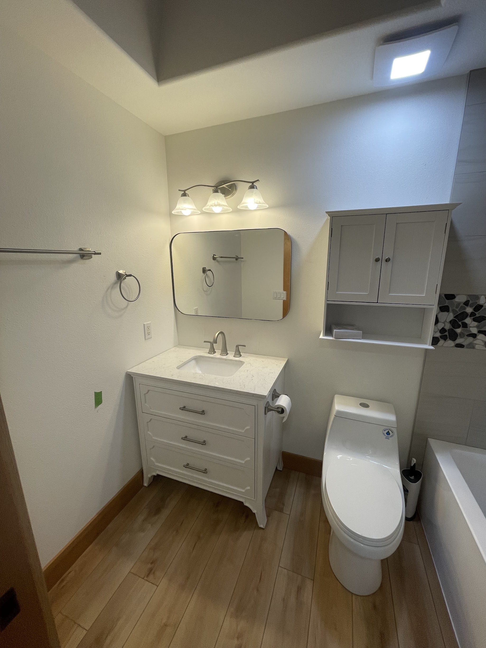A finished bathroom vanity with a quartz counter and round mirror