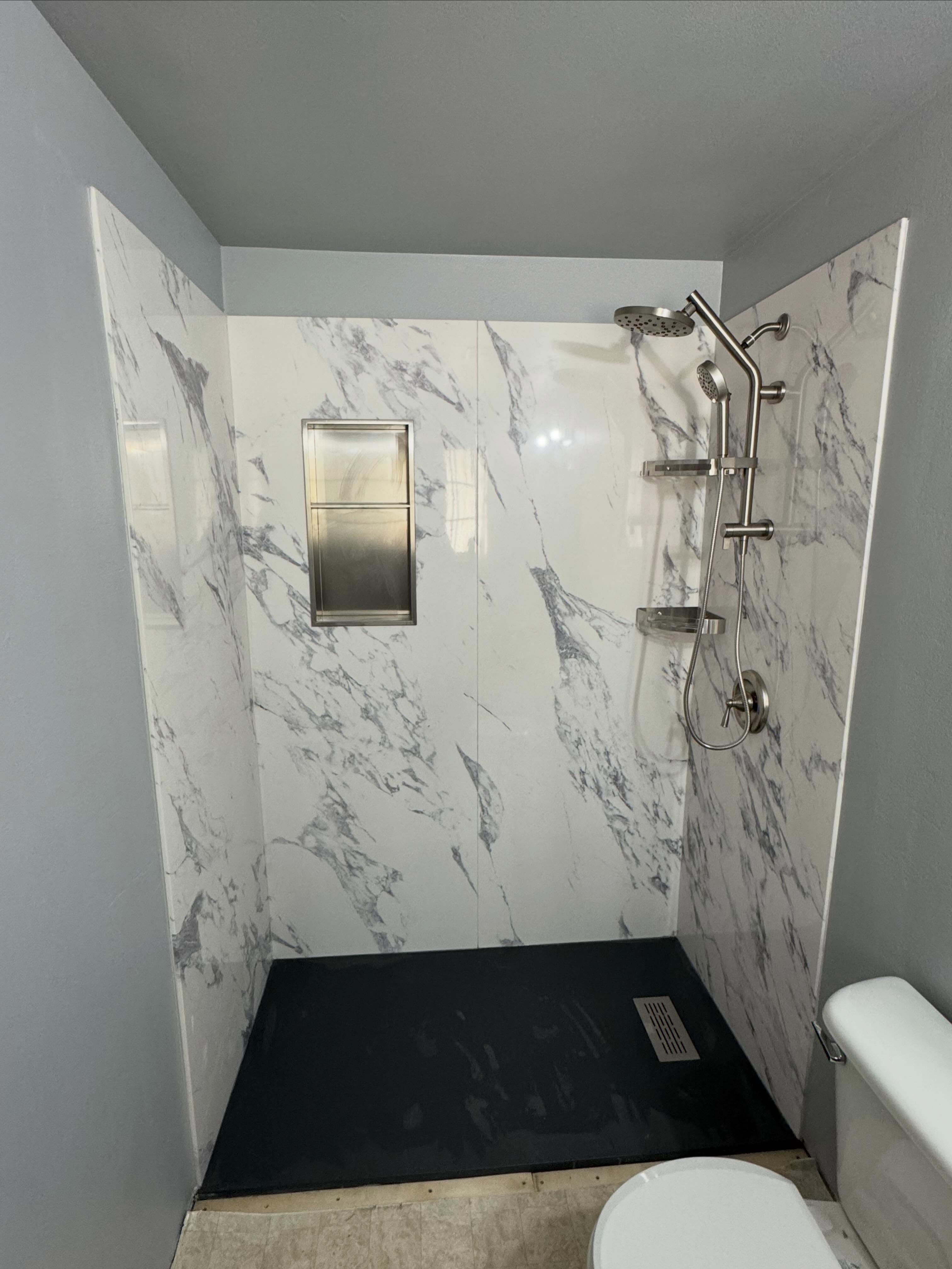A finished marble-look shower surround with a rain shower head