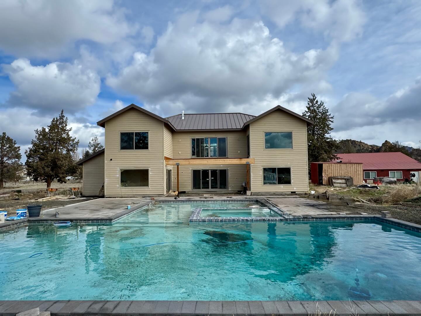 A new home under construction with an in-ground pool being built alongside it